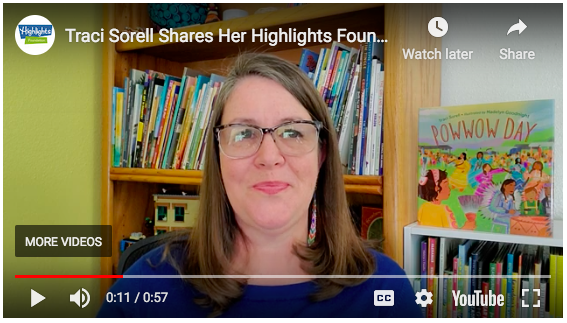 Traci Sorell with her book Powwow Day to her right, and a bookcase filled with books behind her.  It is a screen shot from a YouTube video.