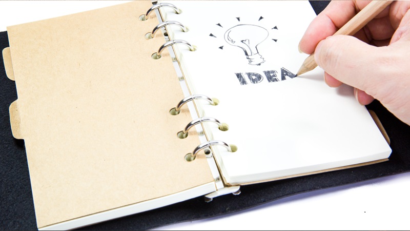 open journal with light bulb and the word "idea" on the page