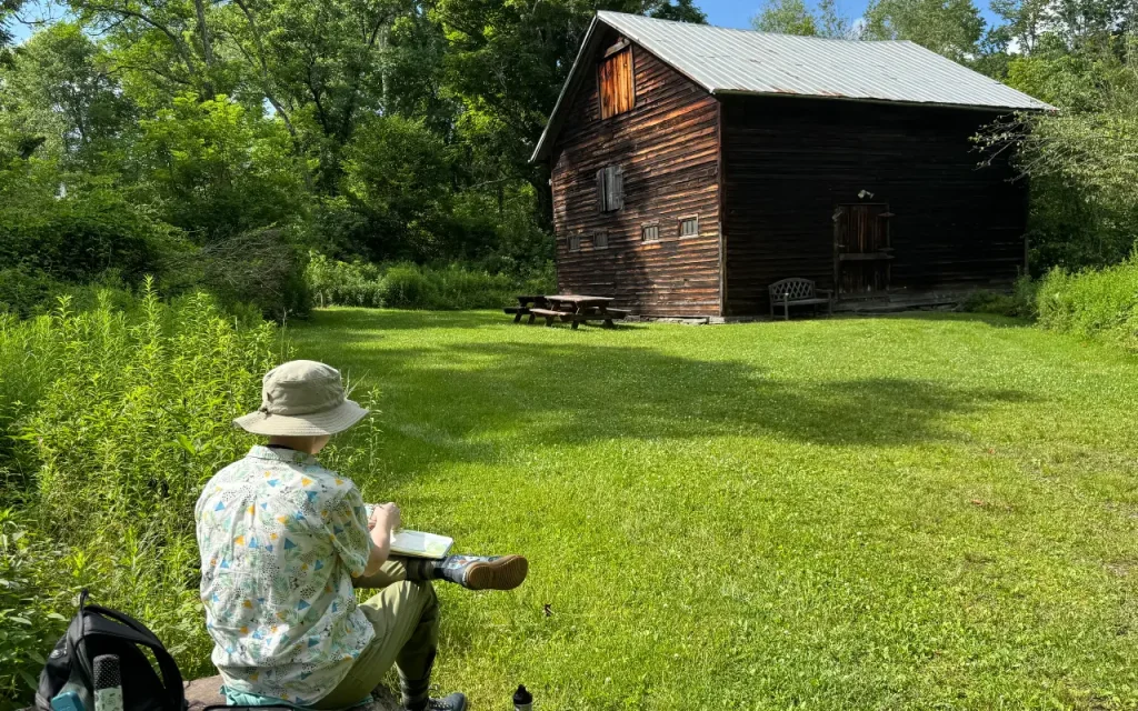 a storyteller sitting in front of the horse barn on campus